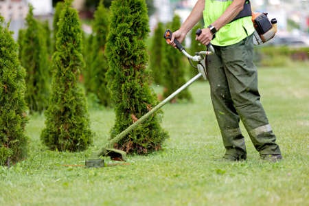 Man Gardener Worker Changing Landscape with String Lawn Trimmerの写真素材