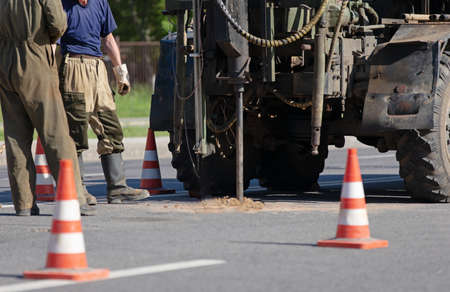 Construction drilling. Industrial workers detecting damage road surface with drill vehicleの写真素材