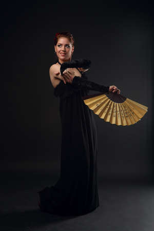 Woman with a Fan dancing flamenco on a black backgroundの写真素材