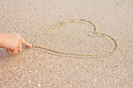 Heart drawn on sand by girlの写真素材