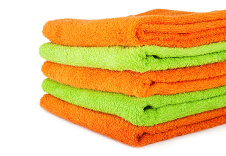 A stack of multicolored orange and green towels on the white backgroundの写真素材