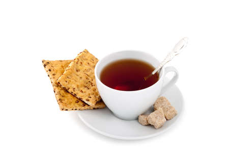 A white cup of a black tea, a brown sugar and crackersの写真素材