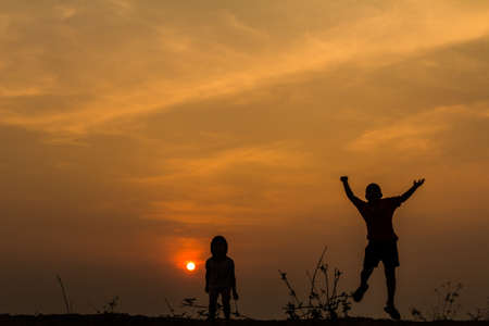 Silhouette, group of happy children playing on meadow, sunset, summertimeの写真素材