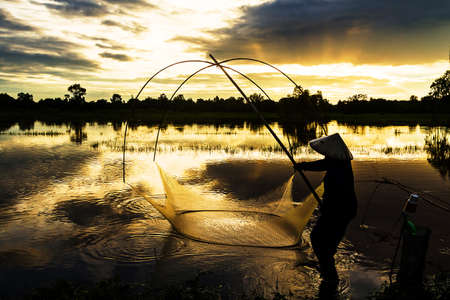 Silhouette of native thai style fish catchingの写真素材