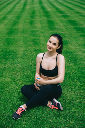 Pretty girl sitting on the grass after trainingの写真素材