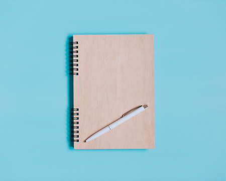 yellow notebook and pen on a blue backgroundの写真素材