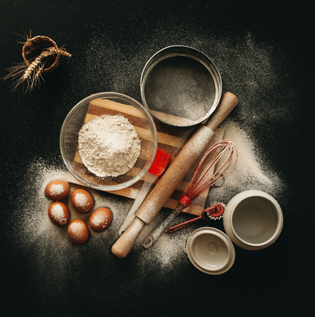Kitchen utensils and baking ingredients: egg and flour on black background, copy-space.の写真素材