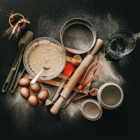 Kitchen utensils and baking ingredients: egg and flour on black background, copy-space.の写真素材