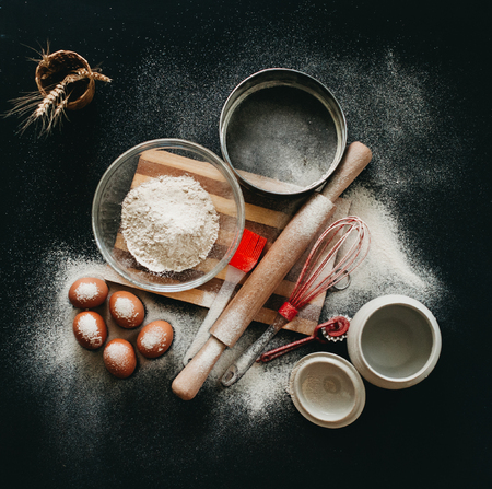 Kitchen utensils and baking ingredients: egg and flour on black background, copy-space.の写真素材