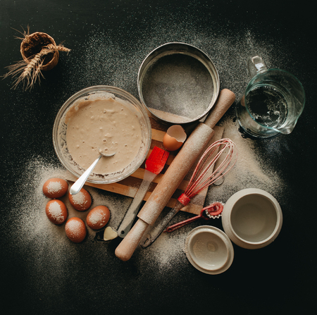 Kitchen utensils and baking ingredients: egg and flour on black background, copy-space.の写真素材