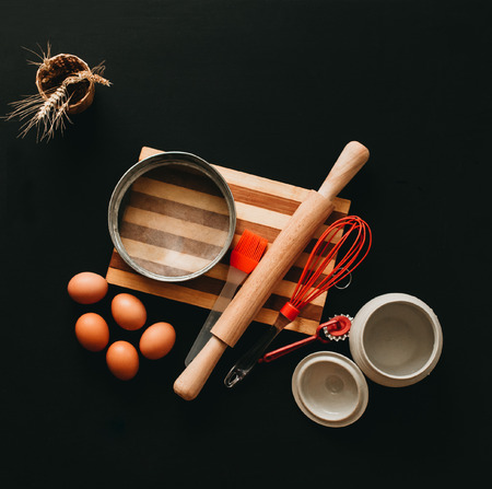 Kitchen utensils and baking ingredients: egg and flour on black background, copy-space.の写真素材