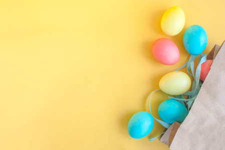 colored easter eggs in a craft bag on a yellow backgroundの写真素材