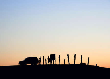 Silhouettes of a car and people on the sky backgroundの写真素材