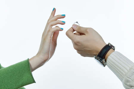 A man is suggesting a ring to a woman, close-up of hands