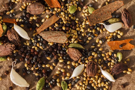 Spices with garlic cloves on brown cloth