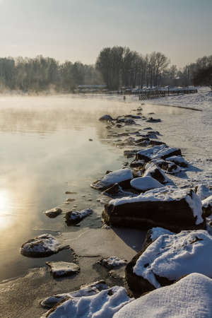 Bank of river with stones and fog in winterの写真素材