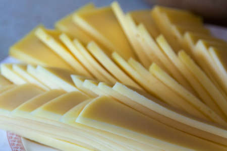 Many slices of yellow cheese on a plate 