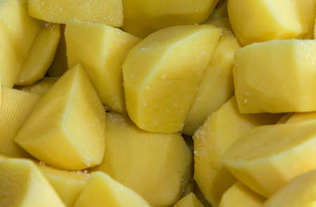 Pieces of sliced yellow raw potatoes with salt