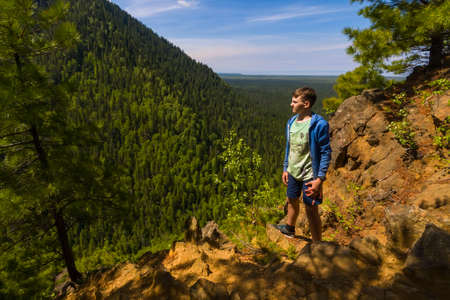 Teenager standing at the rock in siberian forestの写真素材