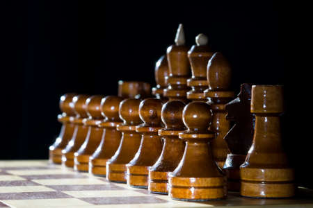 Brown chess wooden pieces on chess board with dark backgroundの写真素材
