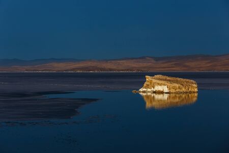Small rocky island at Baikal lake with its reflection with melting iceの写真素材