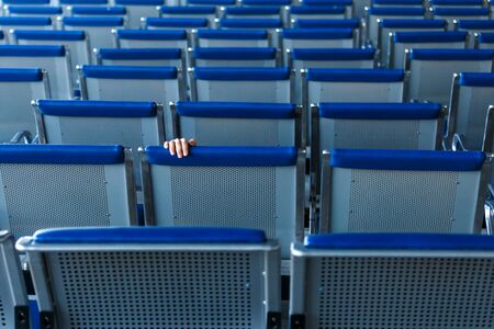 Row of horizontal seats and a human hand in airport hall