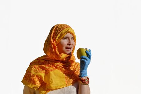 Portrait of a woman in Indian dress and blue protective gloves biting an apple