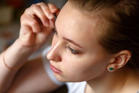 Portrait of a girl applying mascara on her eye lashes view from aboveの写真素材