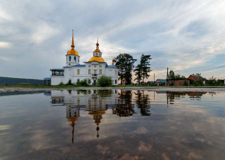 UST-KUDA, RUSSIA - 24 JUNE 2020: Russian rural landscape with an old church and its reflection in waterのeditorial素材