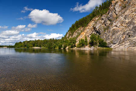A natural landscape of river with clear water, blue sky and clouds and cliff
