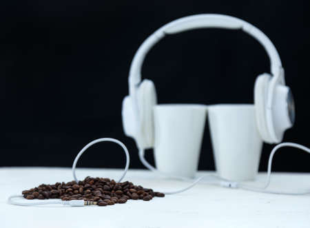 White two mugs with headphones over them with wire connected to coffee beansの写真素材