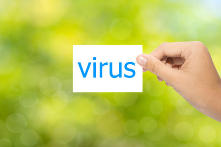 Hand holding a paper virus on green background の写真素材