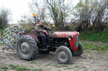 Farmer on old tractor cramps stubble on his field in Serbia. Preparing the country for the autumn plowing.のeditorial素材