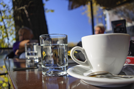 Tavern table outdoors with a glass and coffee cup.の写真素材