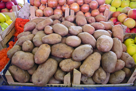 Fresh potatoes on a market stall in an apple box waiting on customers.の写真素材
