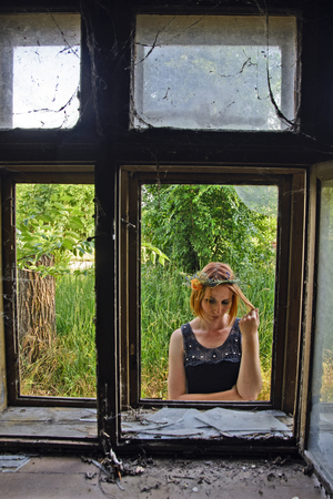 Young girl at the window of the old abandoned house.の写真素材