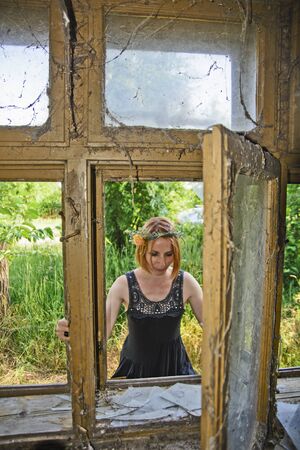A young woman looks from the street to an old ruined house.の写真素材