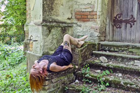 Sad and lonely young woman in black lying on the old stairs.の写真素材
