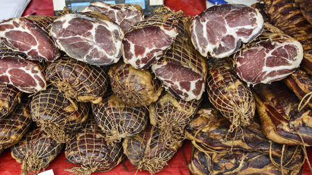 Dried and smoked ham and other products on the open booth of the traditional fair.の写真素材