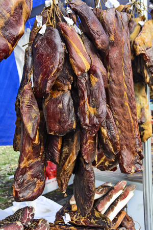 Dried and smoked ham and other products on the open booth of the traditional fair.の写真素材