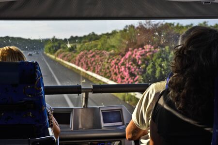 Travel through Greece and view of passengers through the front glass of a double deck bus.の写真素材