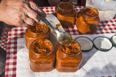 Freshly cooked and fresh Ajvar in jars on the table. Waiting for tasting.