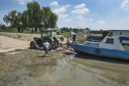 Novi Becej, Tisa River, Serbia May 14, 2017. A group of men are pulling a yacht out of the river for repair on the same.のeditorial素材