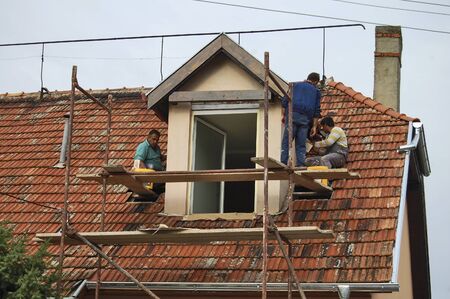 Zrenjanin, Serbia, July 17, 2013. A group of workers is working on the reconstruction of the attic of an apartment building.のeditorial素材