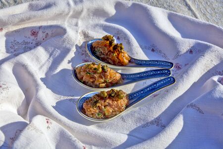 Specialty salmon meat with spices on the table. The meat is decoratively presented in ceramic spoons.の写真素材