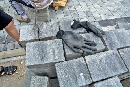 A large pile of stacked concrete pavement slabs and workers' gloves left on them.の写真素材