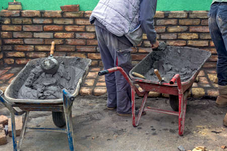 Parked trolley, mortar and tools to help build the building. Several of the masons present use mortar from the cart.の写真素材