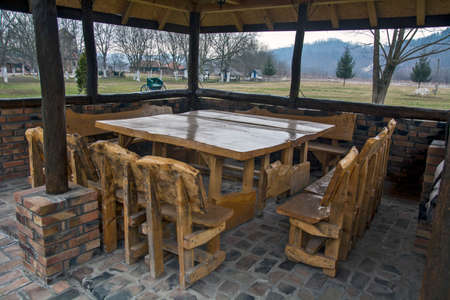 Restaurant with wooden benches and massive tables in the open-air restaurant. The weather is cold and foggy, so tourists prefer to stay indoors with heating.の写真素材