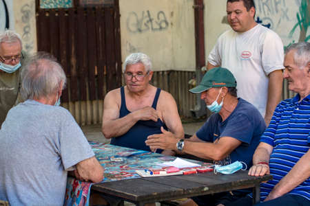 Zrenjanin, Serbia, July 29, 2020. Older gentlemen and pensioners play cards every day in the shade of a large tree. There are always curious observers.のeditorial素材