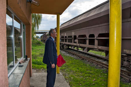 Zrenjanin, Serbia, November 16, 2015. Entry of a freight train into the railway station. The railroad officer is vigilantly watching every freight car that passes by him.のeditorial素材
